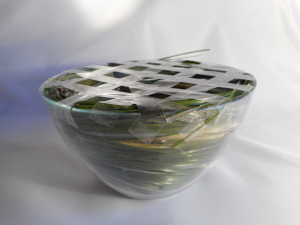 В нижней части чаши мы закрепляем зеленый с помощью пластилинового цветочника, а по его краям склеиваем ленту «якорь» в нескольких местах, что в итоге удержит траву в нужном месте